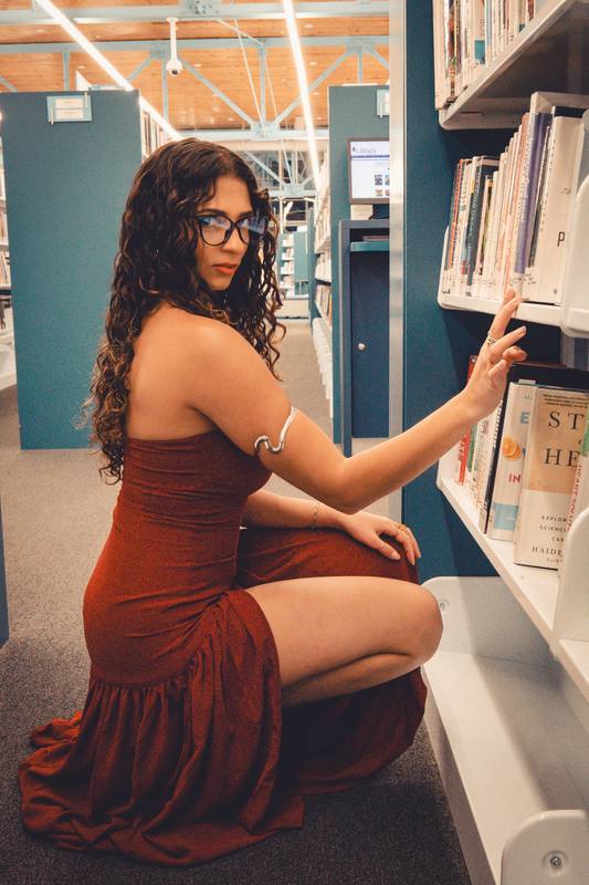 Woman in a rust dress between library shelves