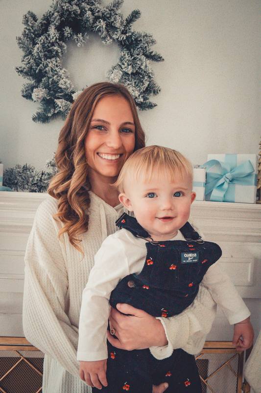 Mother holding her smiling baby by a wreath