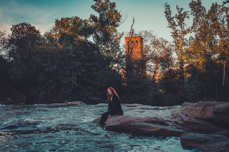 Woman sitting by a river at sunset