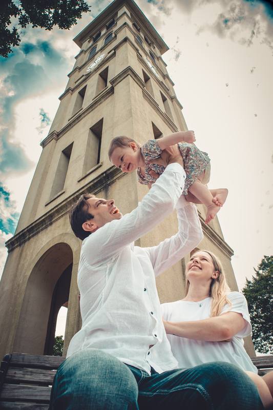 Parents lifting their child in front of a stone tower
