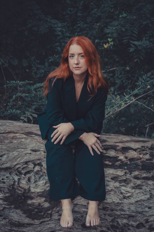 Woman in a dark suit sitting on the rocks at Glendale Shoals